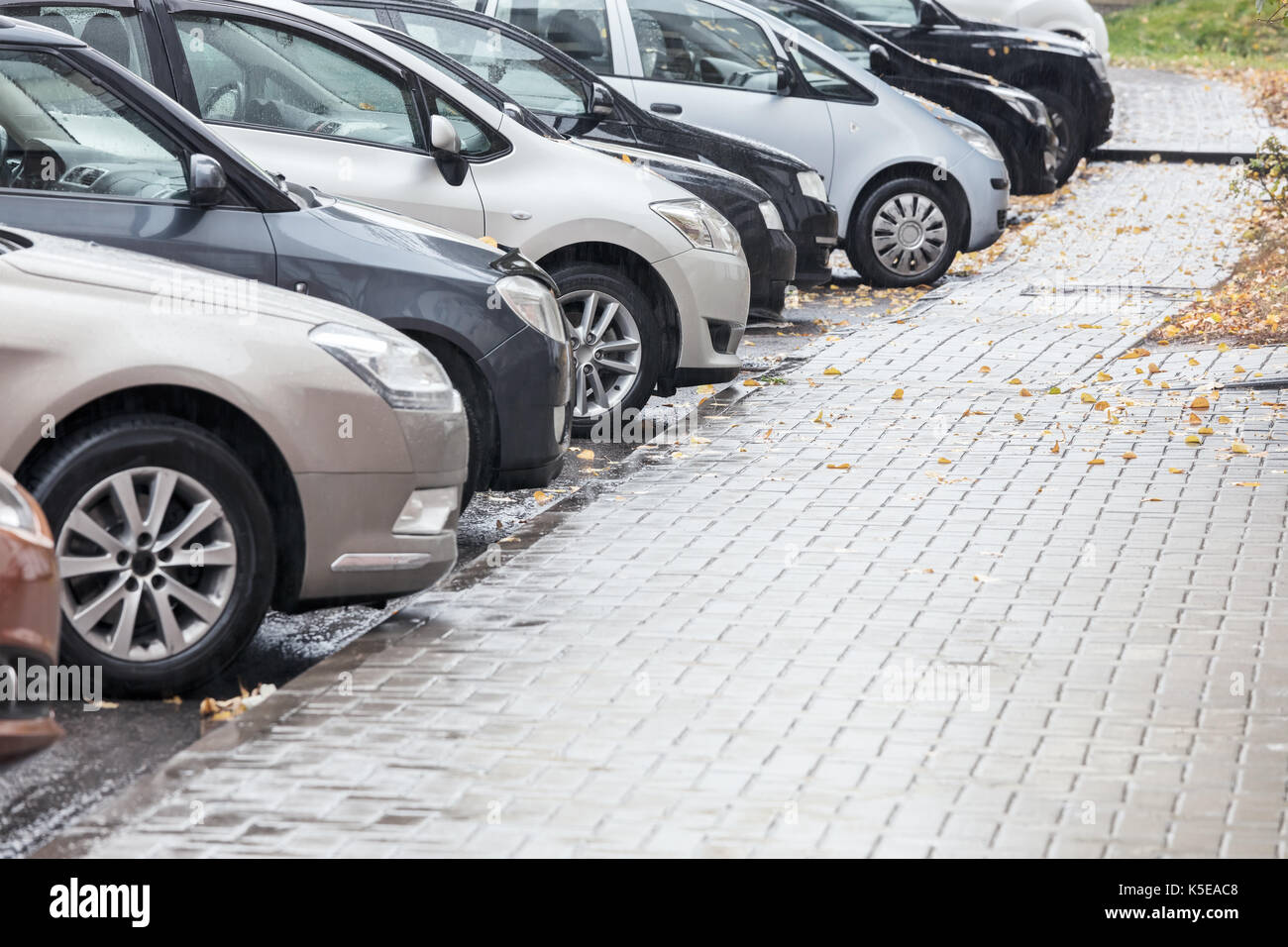 several cars parked in a parking lot on a rainy day Stock Photo