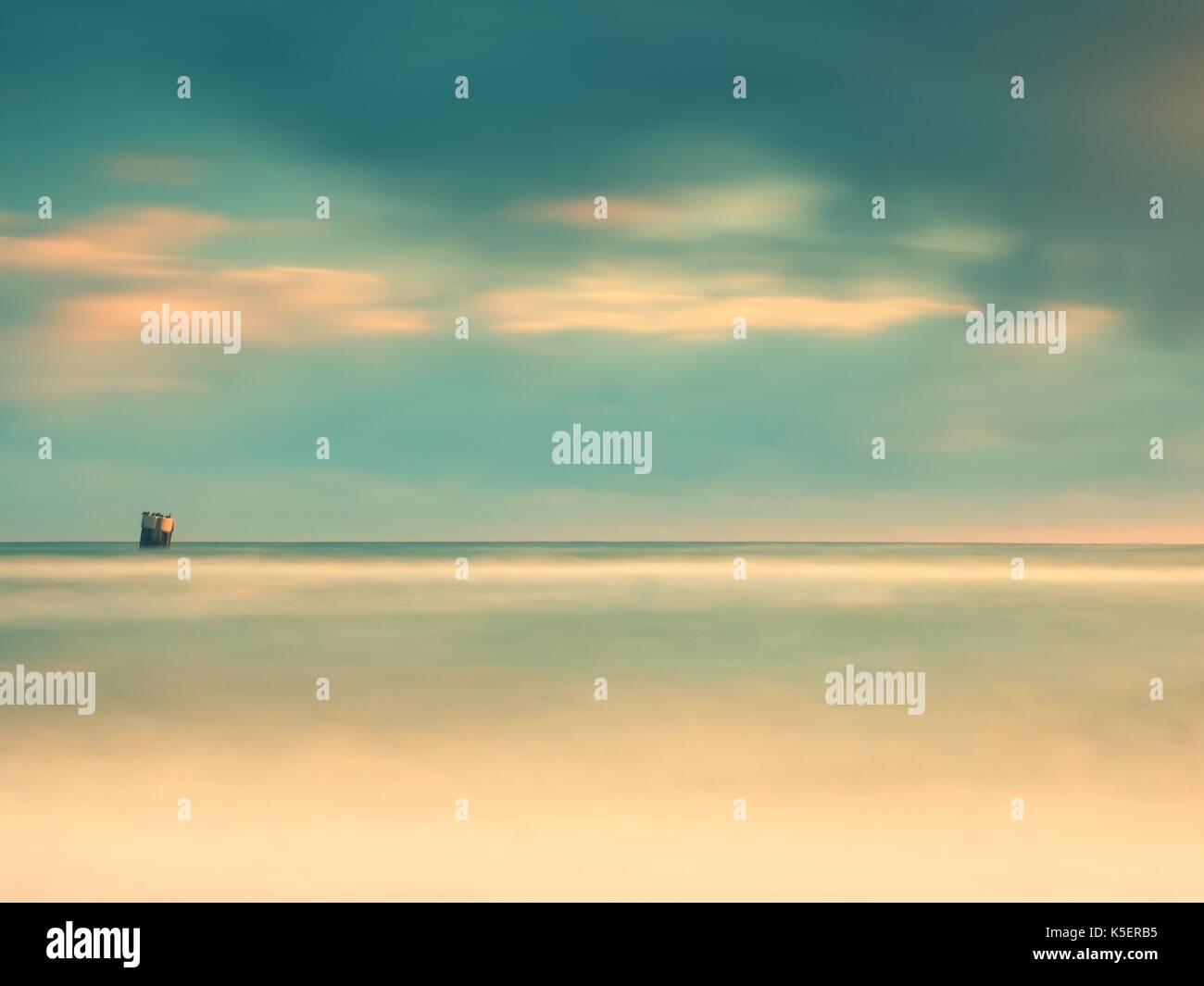 Concrete block island in sea with sitting gull in and cormorant. Stone