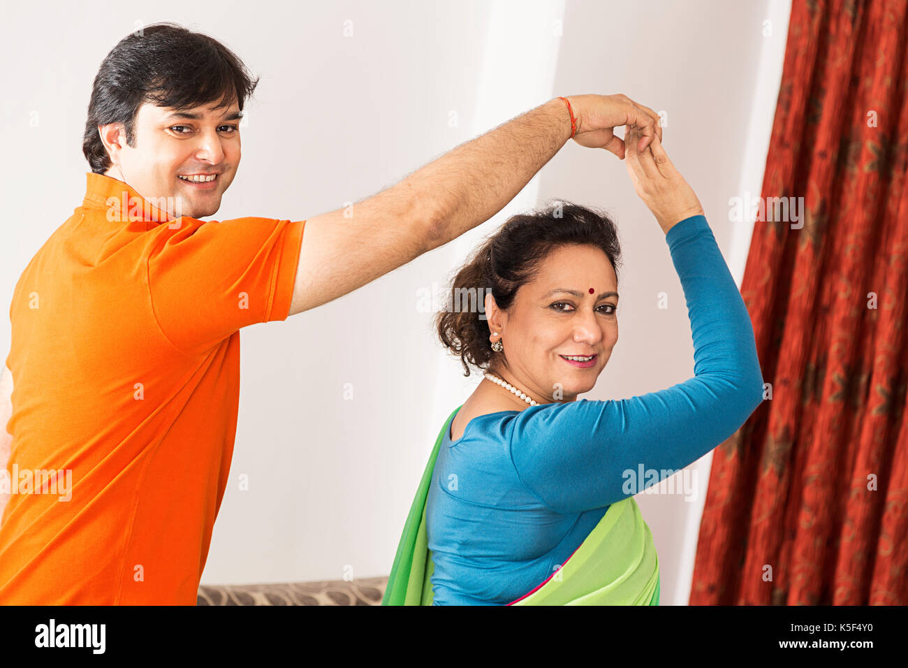 Adult Son And Senior Mother Dancing Rotating Having fun at home Stock Photo