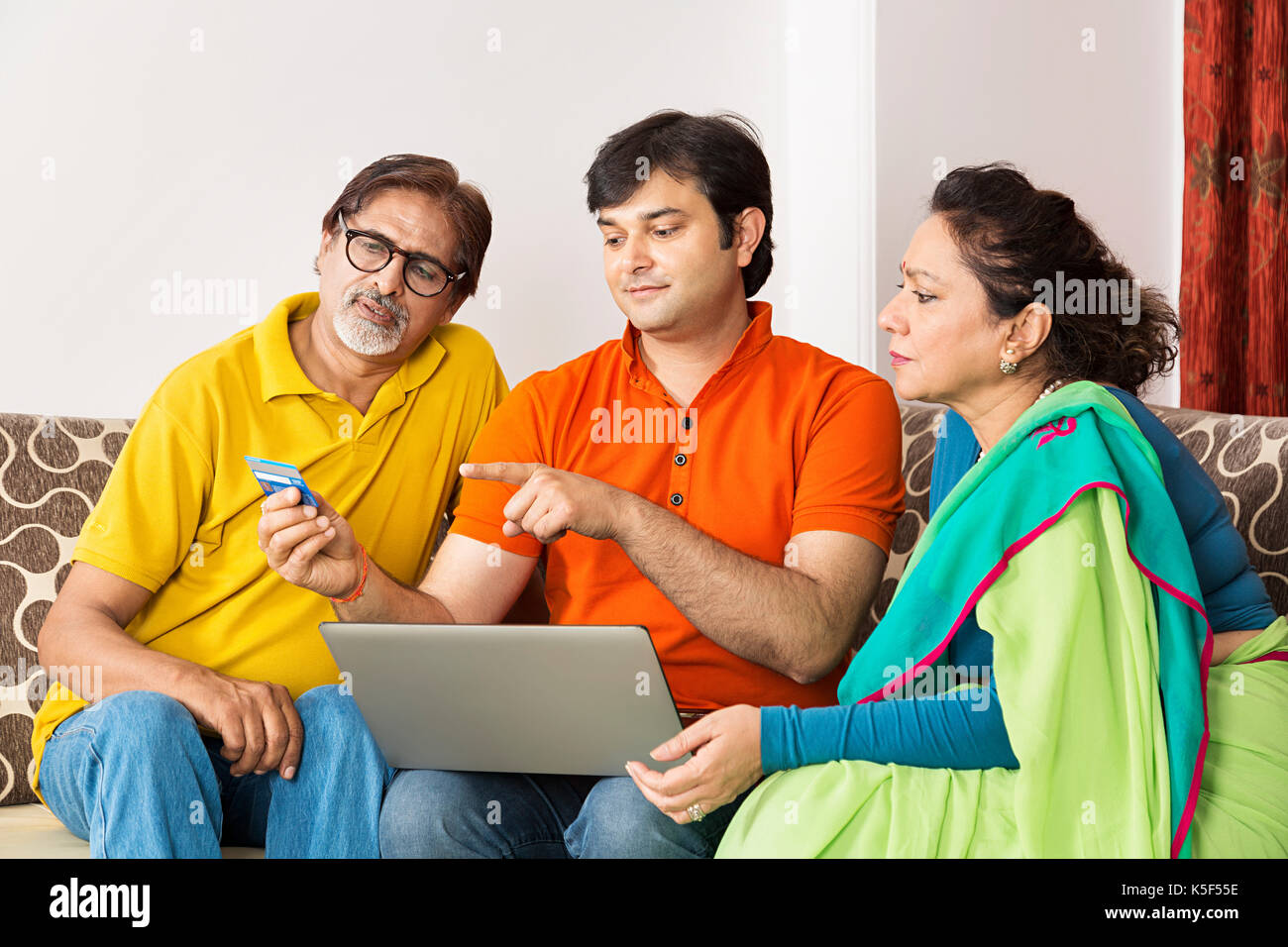 Indian Son And Senior Parents Laptop Credit Card Pointing Online Shopping Stock Photo