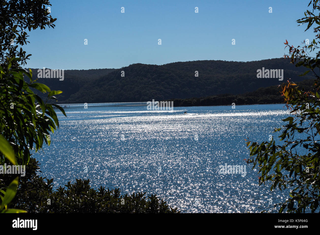 Sun shining onto river against headland and blue sky Stock Photo - Alamy