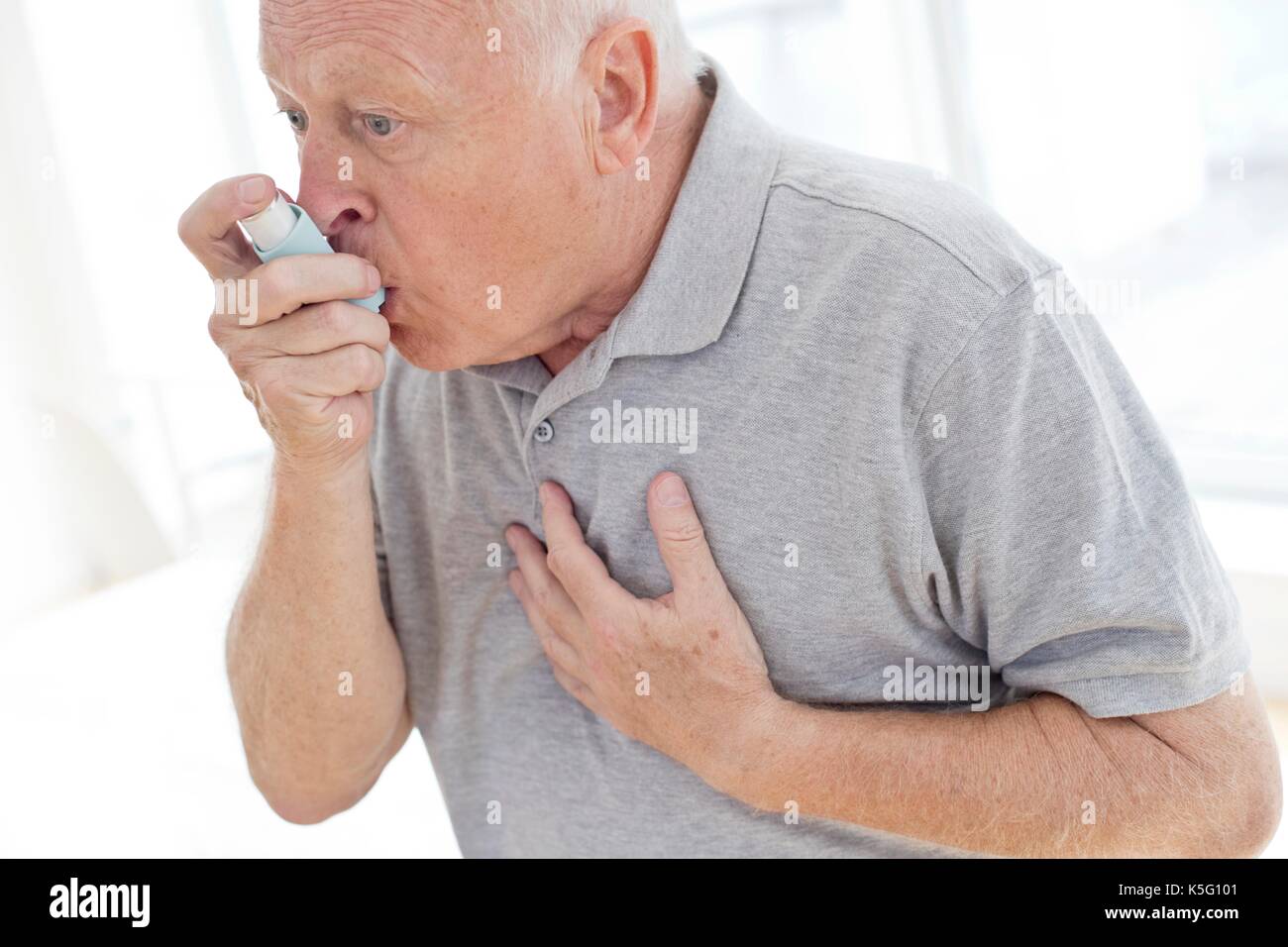 Senior man using inhaler, holding chest. Stock Photo