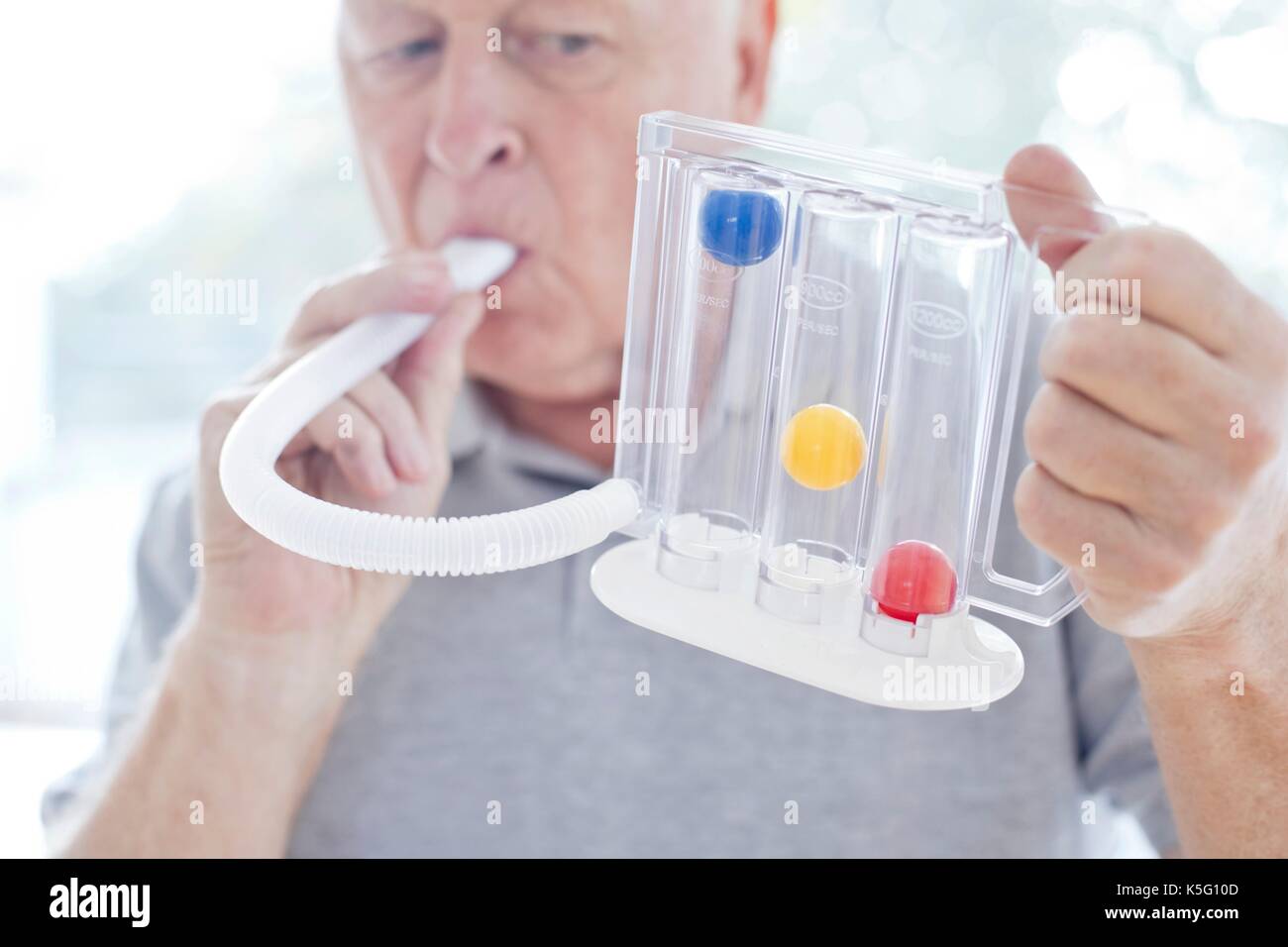 Senior man using an incentive spirometer. Stock Photo