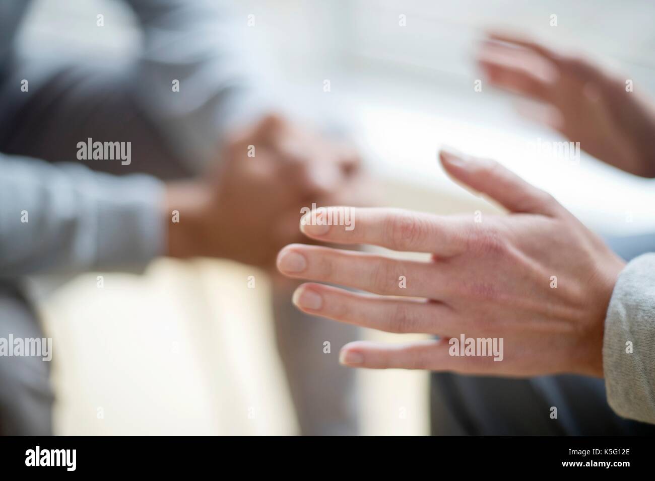 Woman gesturing with hands, man in background. Stock Photo