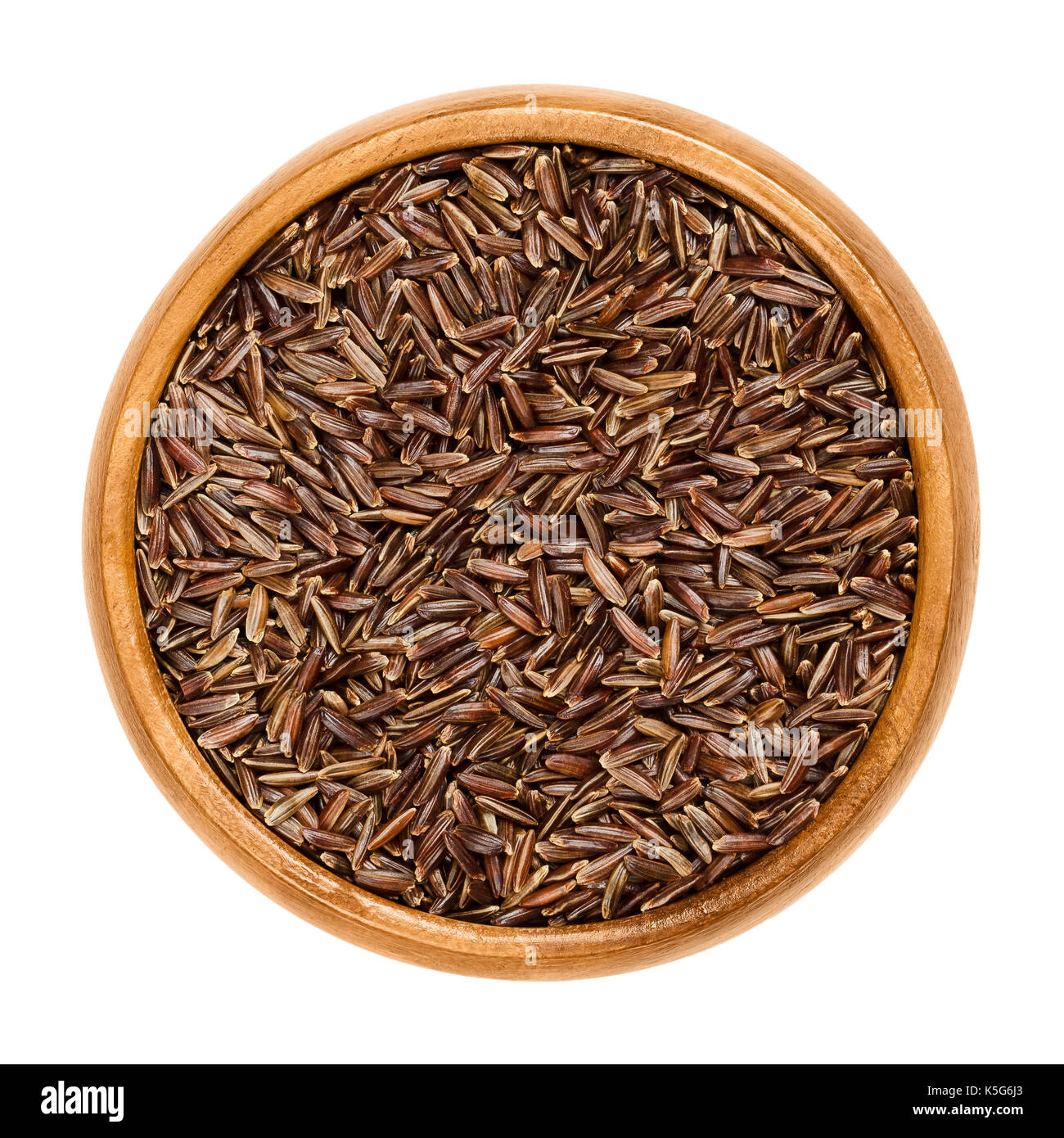 Camargue red rice in wooden bowl. Variety of red wild rice with brownish red colored grains, cultivated in southern France. Isolated macro food photo. Stock Photo
