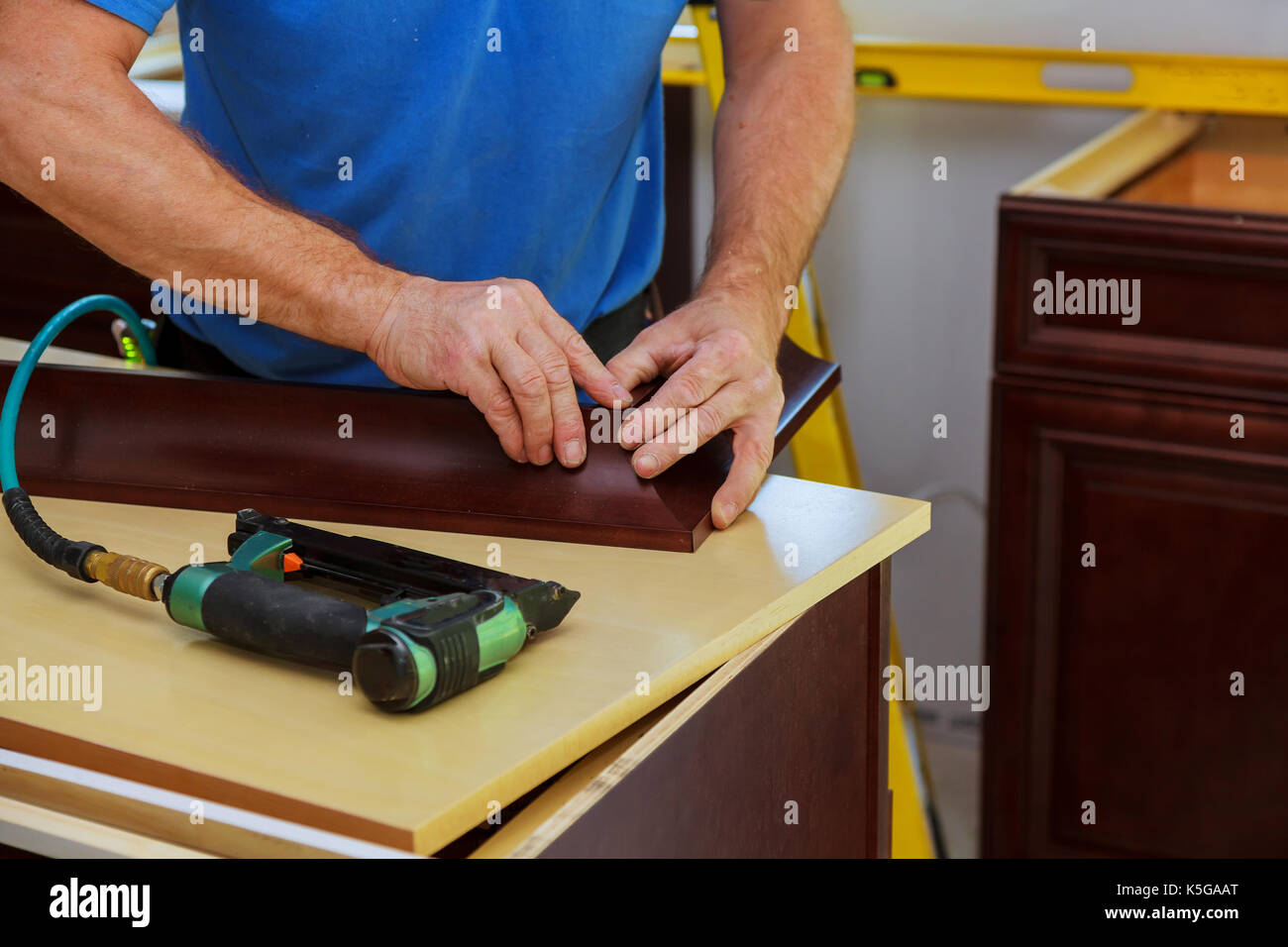 Carpenter brad using nail gun to Crown Moulding on kitchen