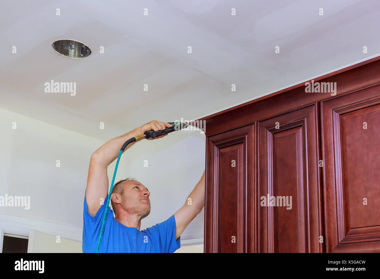 Carpenter brad using nail gun to Crown Moulding on kitchen