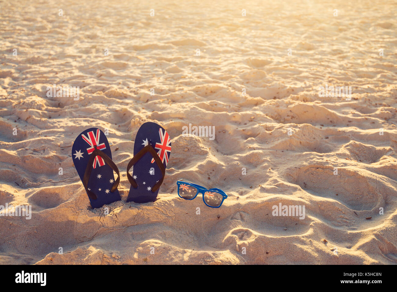 Thongs and sunglasses in sand on a beach, Australia day concept Stock Photo