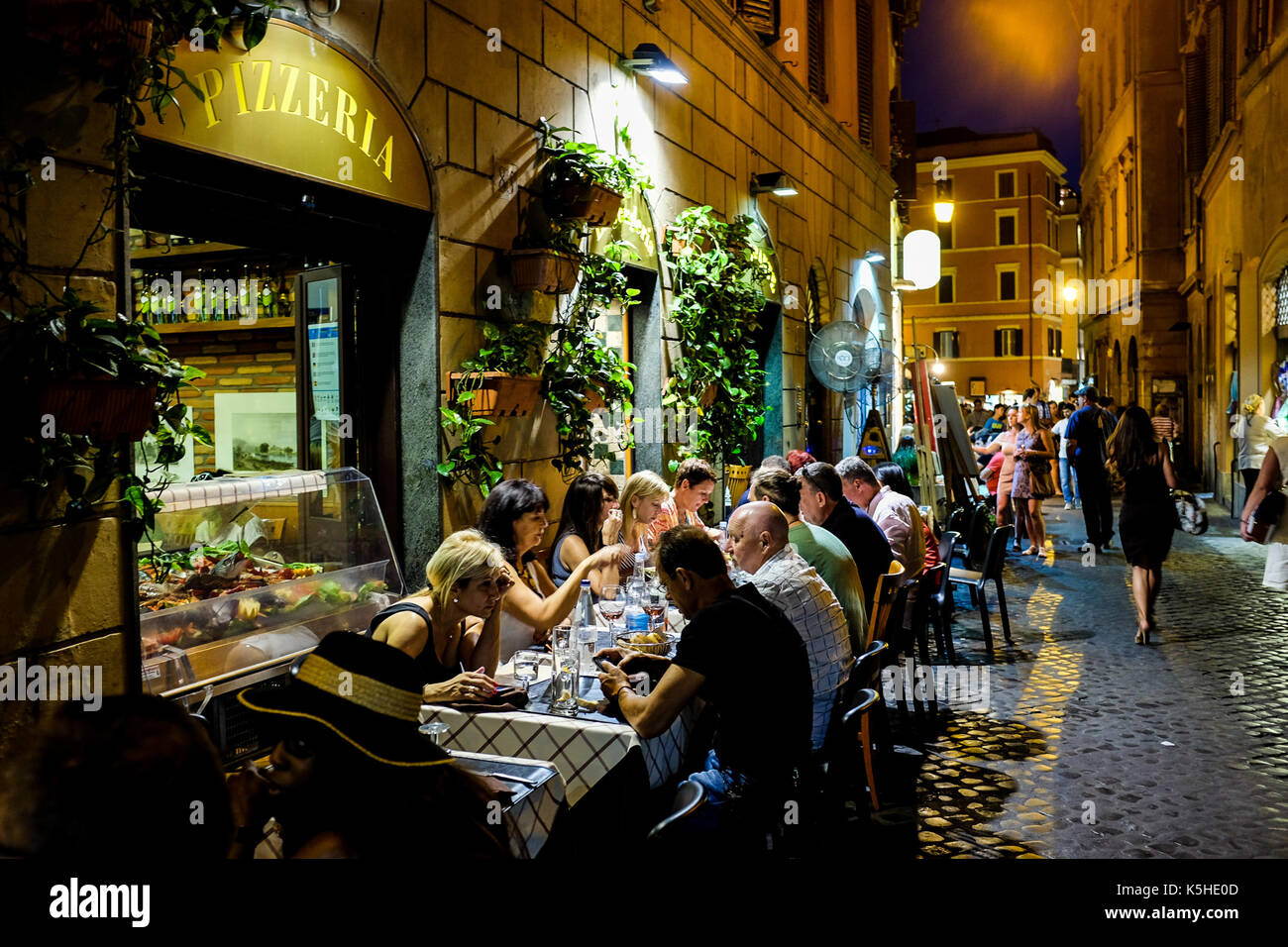 People and tourists eat at a pizzeria in Rome, Italy on July 4, 2016. Stock Photo