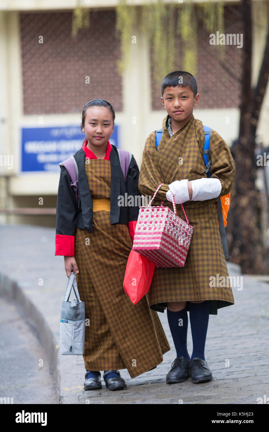 Schoolchildren on their way to the town school wearing traditional Bhutanese costume as uniform in Thimphu, Western Bhutan. Stock Photo