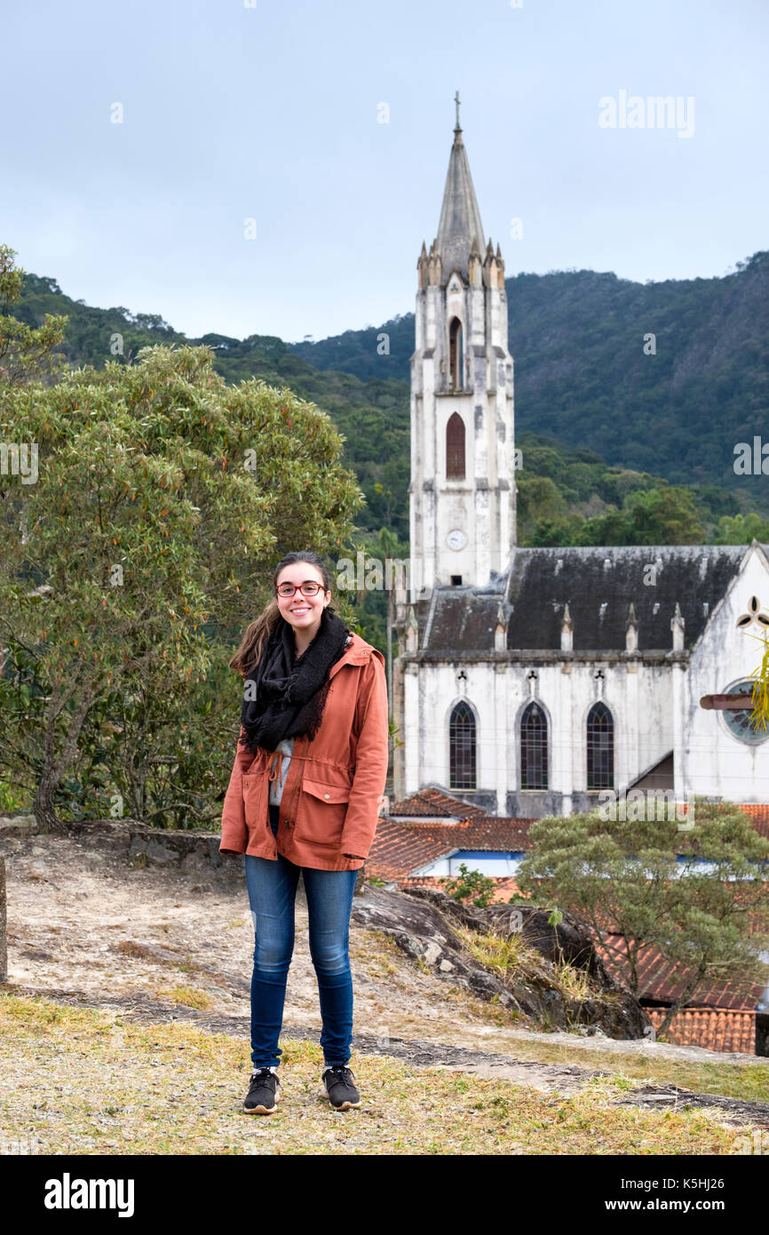 Eighteen year old girl posing for a portrait smiling in front of Caraca Sanctuary's neo-gothic church, Minas Gerais, Brazil Stock Photo