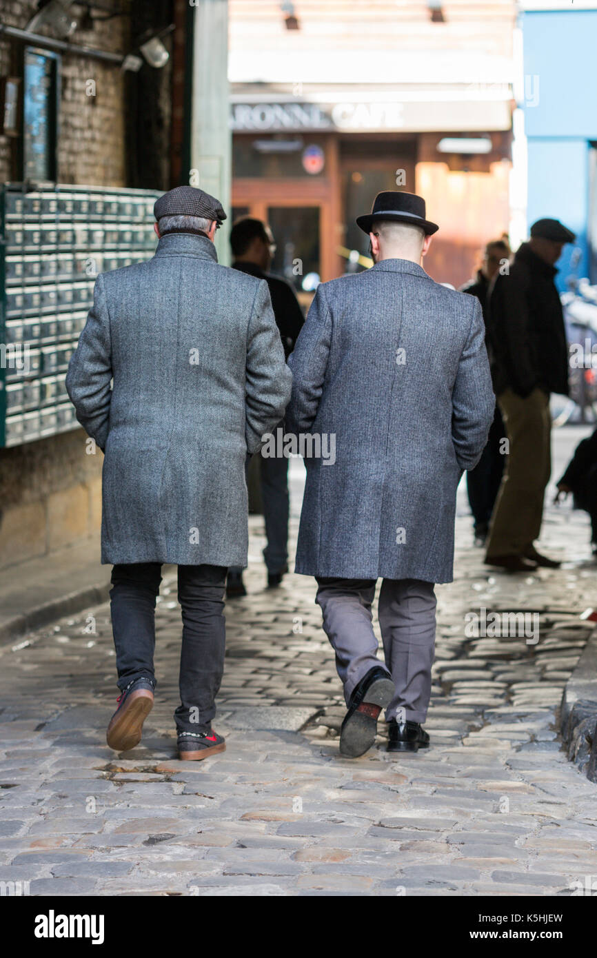 Two men in elegant coats and hats walk out of Passage Lhomme off rue de Charonne in the 11th, Paris. Stock Photo
