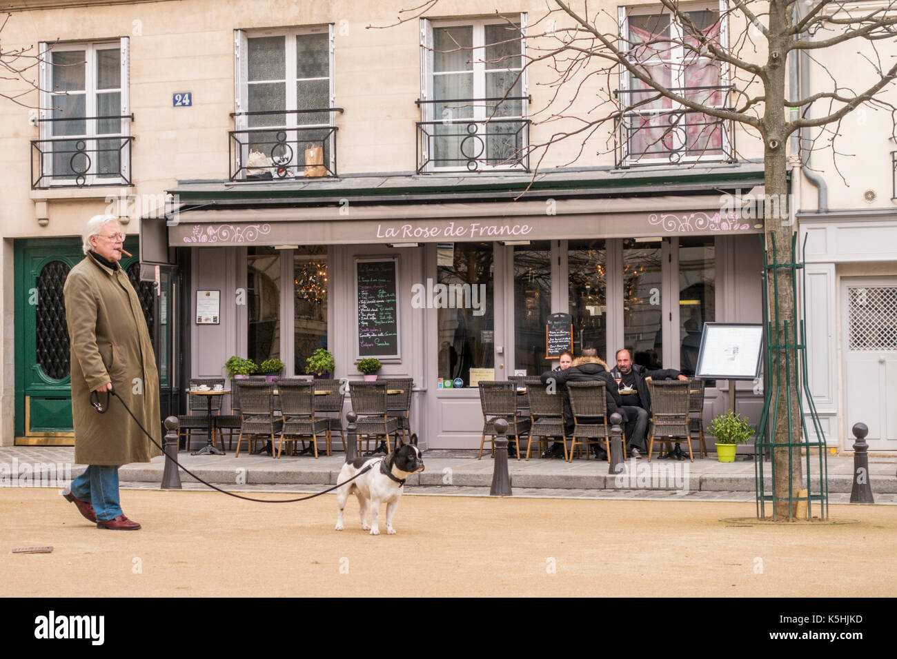 Man in raincoat walking his dog in Place Dauphine on Île de la Cité Stock Photo