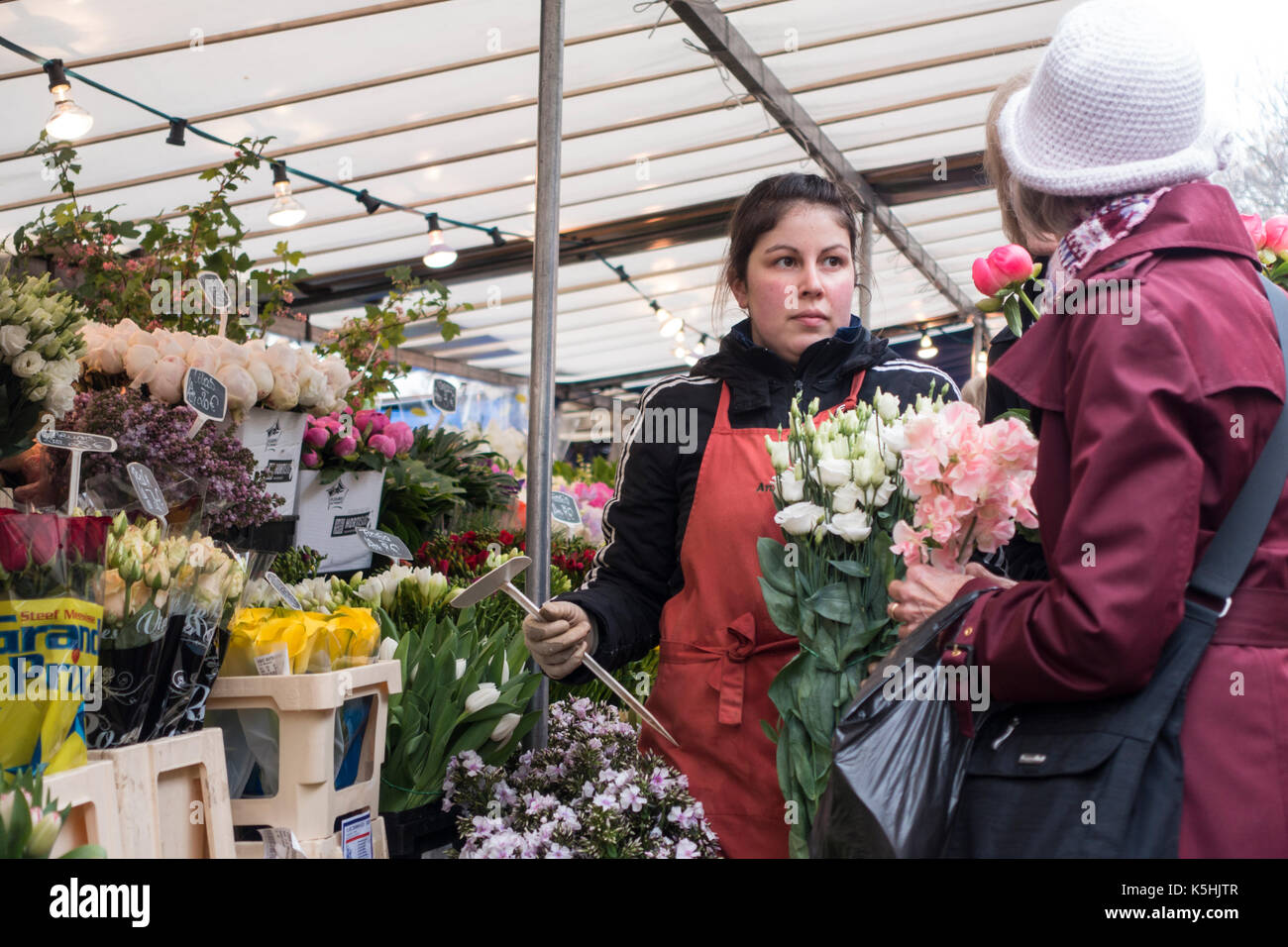 Vendor sells flowers to a customer at a flower stand at the Bastille market in Paris, France Stock Photo