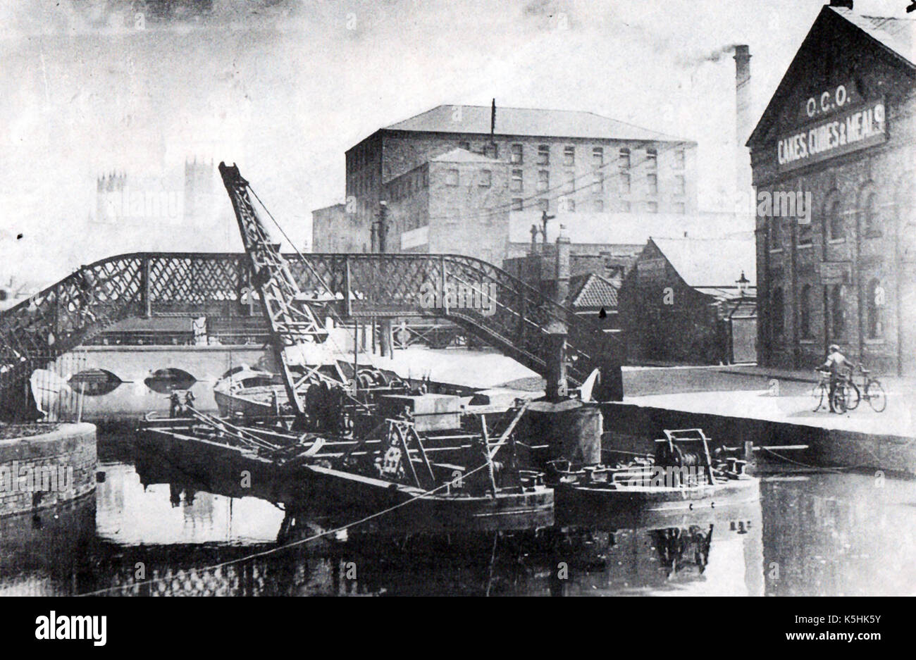 Lincoln England - A dredger  dredging the River Witham near a dockside meal factory & warehouses. Stock Photo
