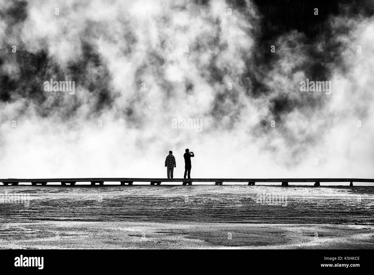 Silhouettes of tourists on a footbridge at steamy Grand Prismatic Spring, Yellowstone National Park, Wyoming, USA. Stock Photo
