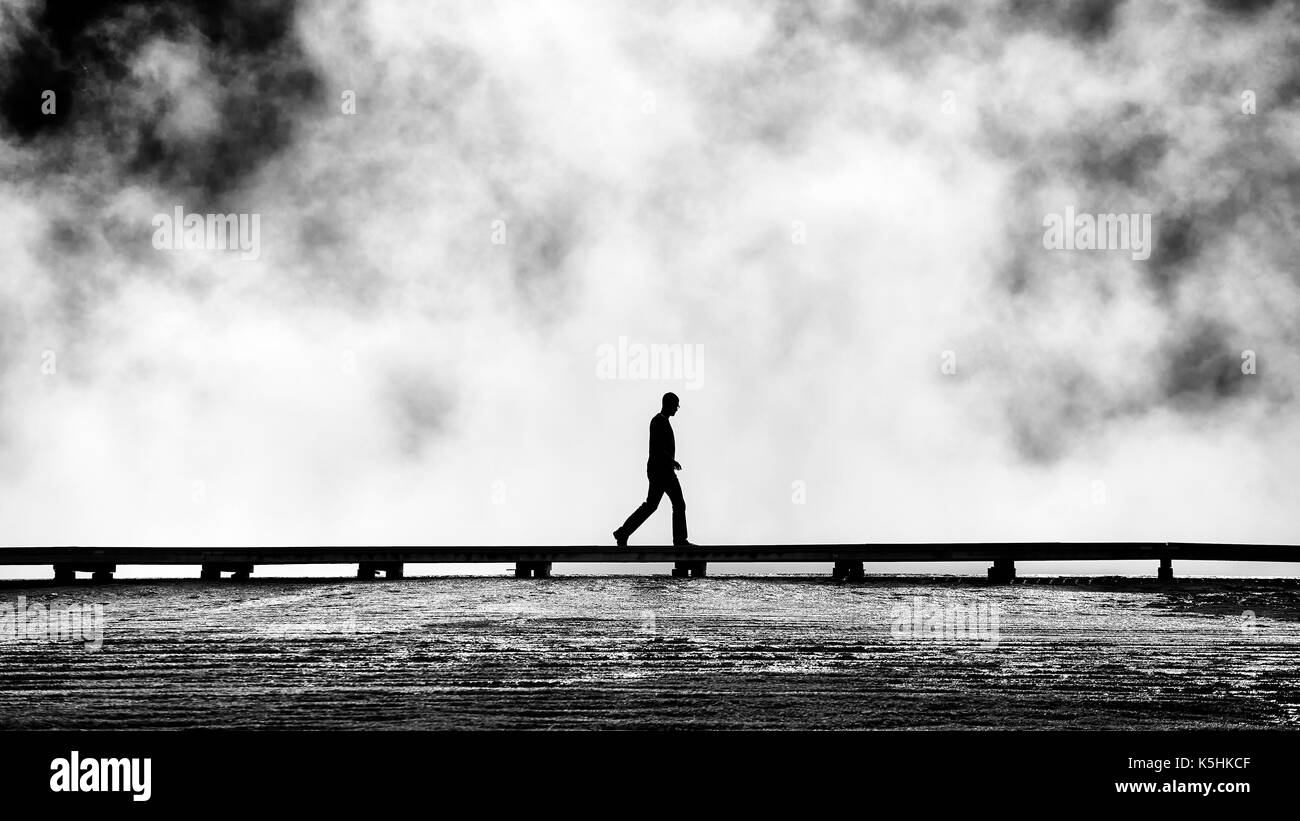 Silhouette of tourist on a footbridge at steamy Grand Prismatic Spring, Yellowstone National Park, Wyoming, USA. Stock Photo
