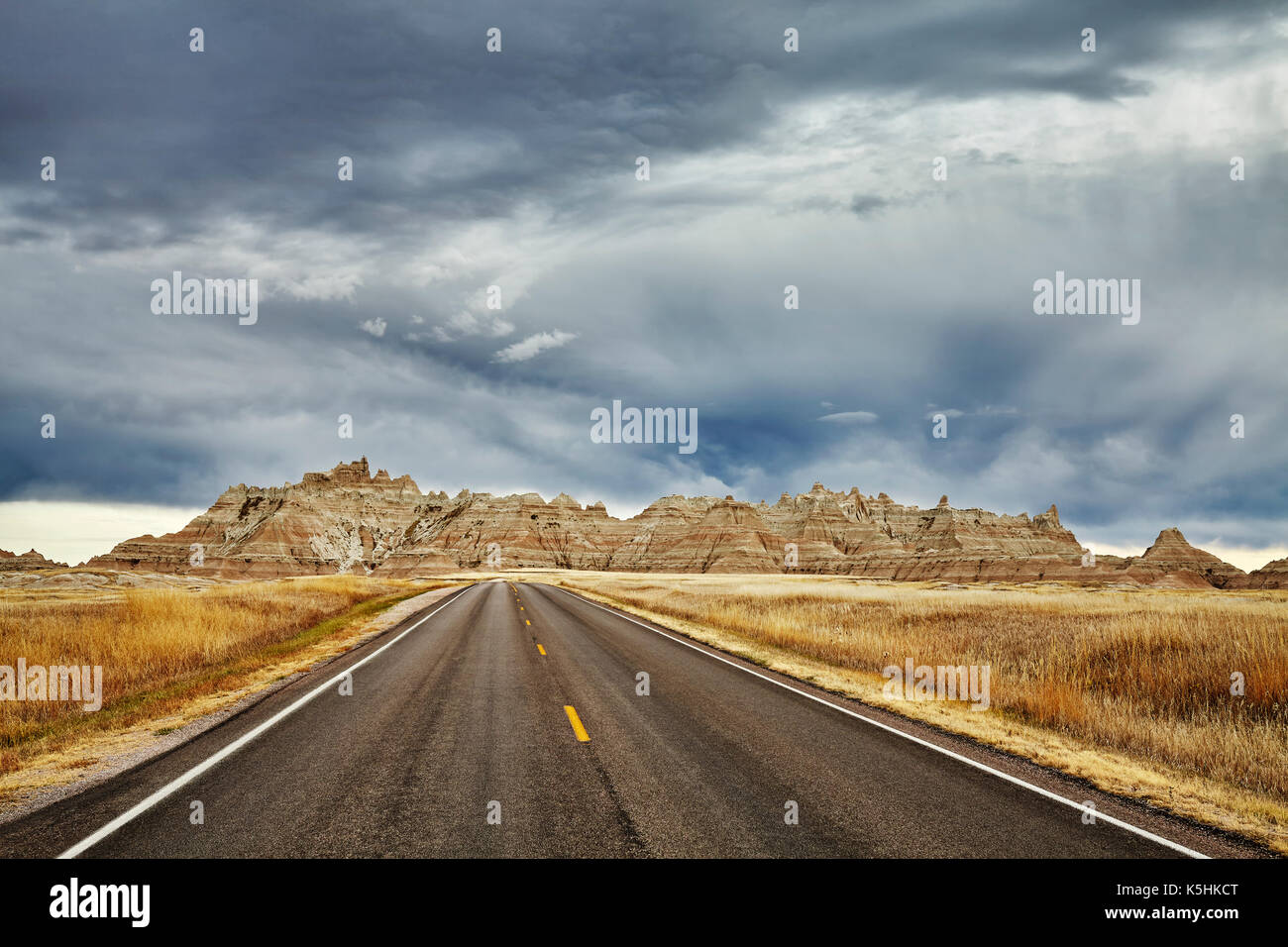 Picturesque road in Badlands National Park with stormy sky, travel concept background, South Dakota, USA. Stock Photo