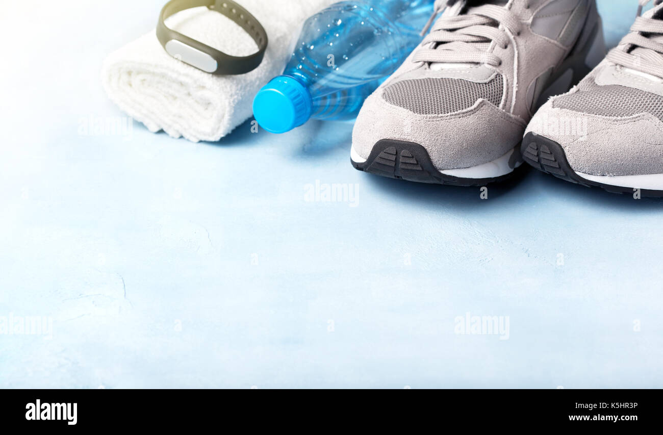 gray sneakers, water bottle, white towel and fitness bracelet on a blue background Stock Photo