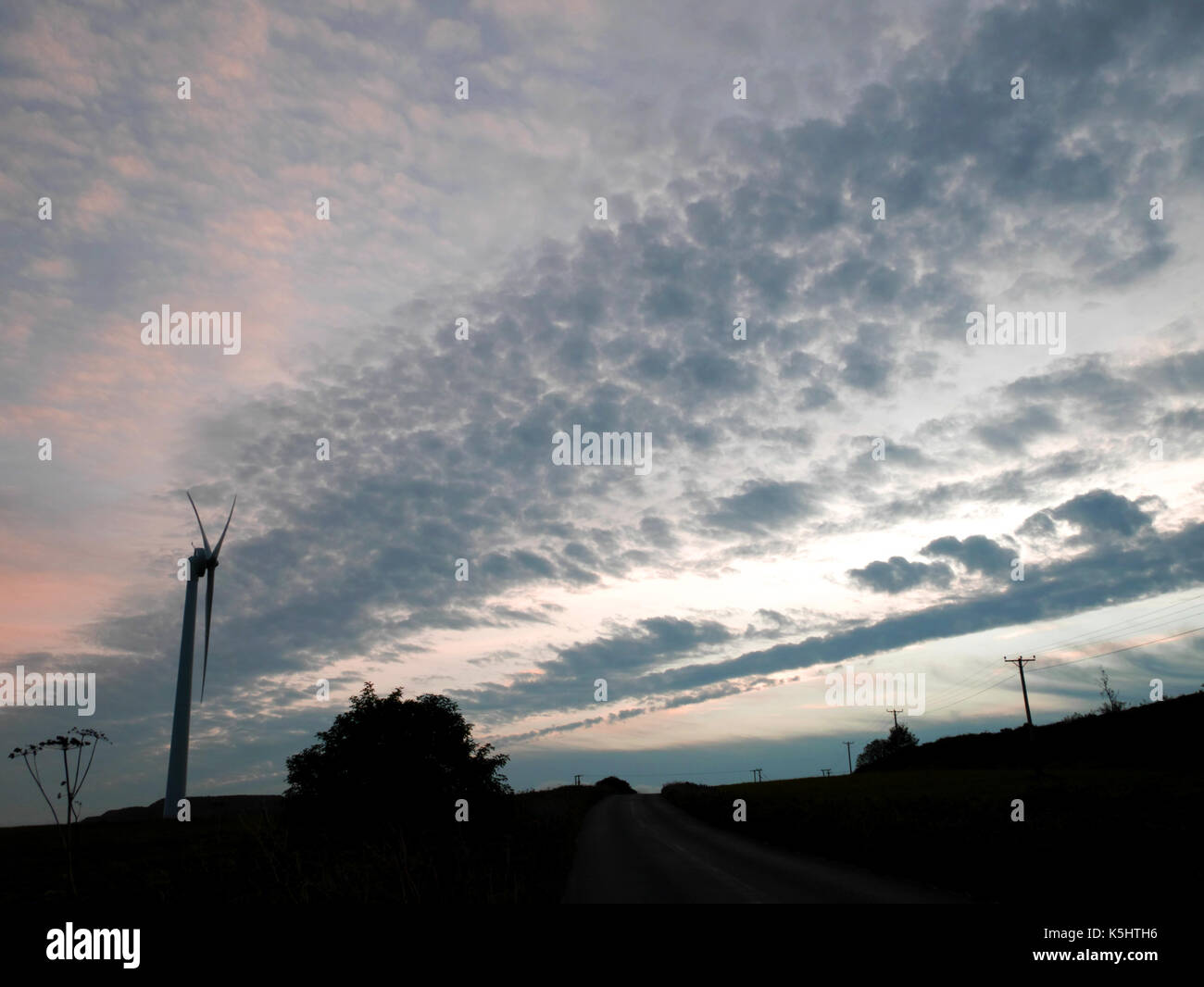 A wind turbine silhouetted against the evening sky near St Austell, Cornwall. Stock Photo