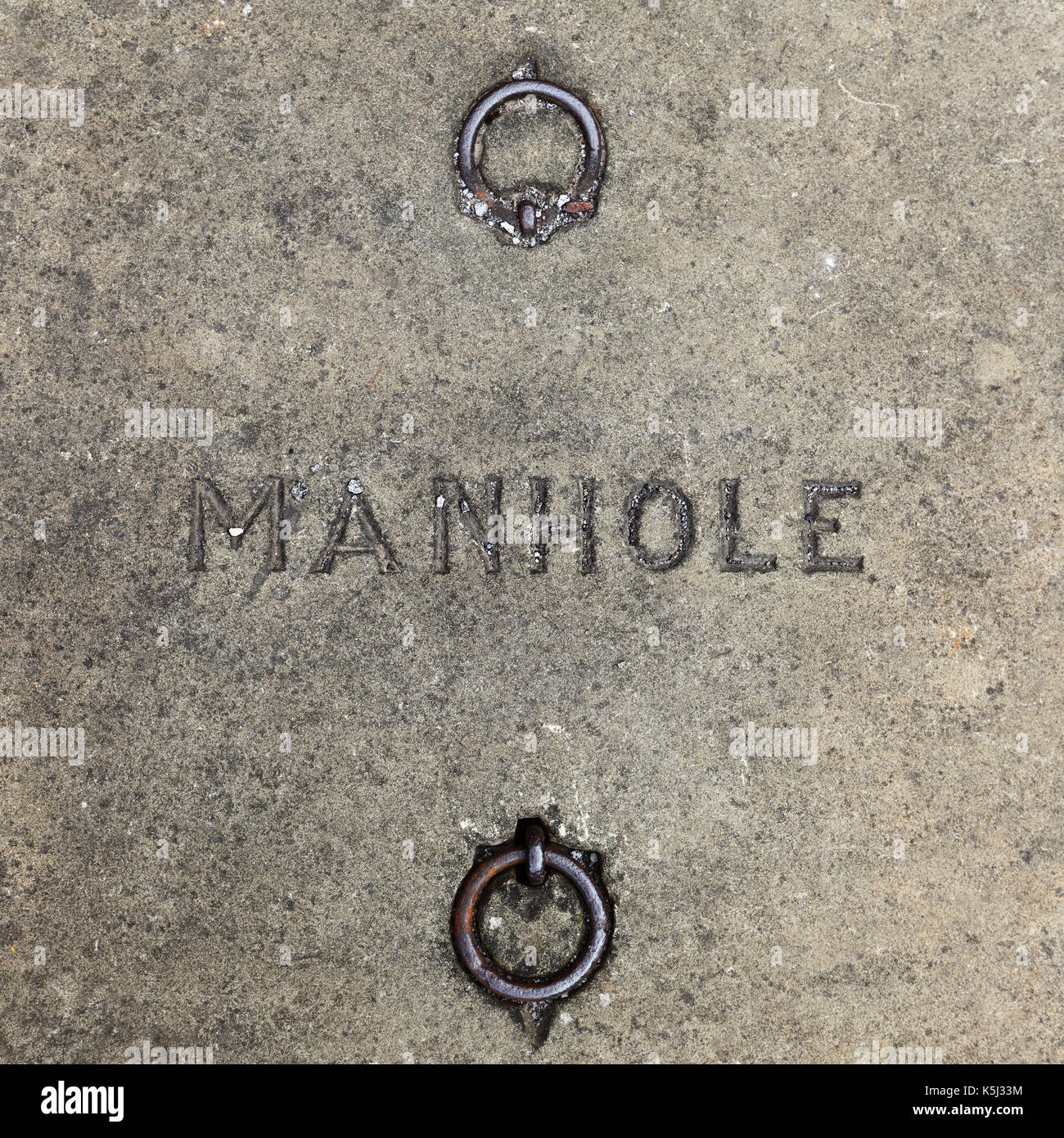 Concrete manhole cover with iron ring handles. Stock Photo