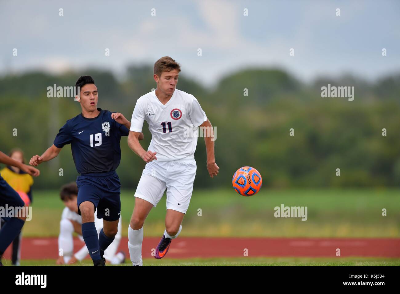 Opposing players pursuing a loose ball during a high school soccer (football) match. USA. Stock Photo