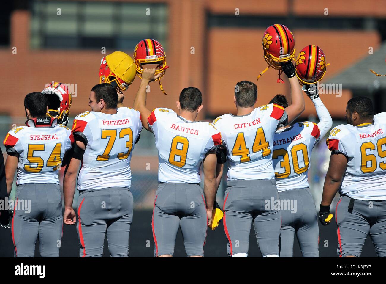 Team members raise helmets in salute following the playing of the 'National Anthem.' USA. Stock Photo
