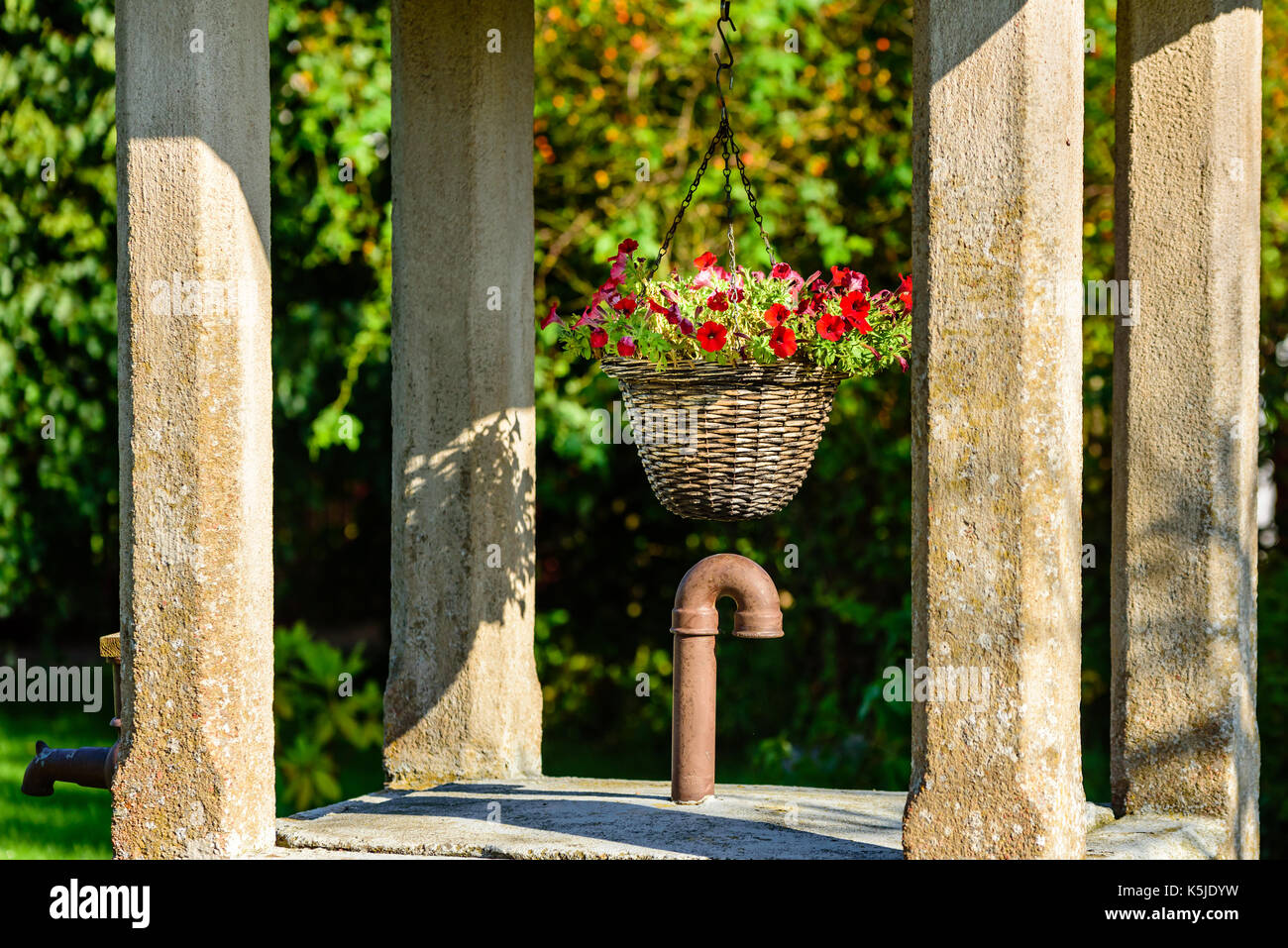 Flower basket hanging inside concrete public water well Stock Photo Alamy