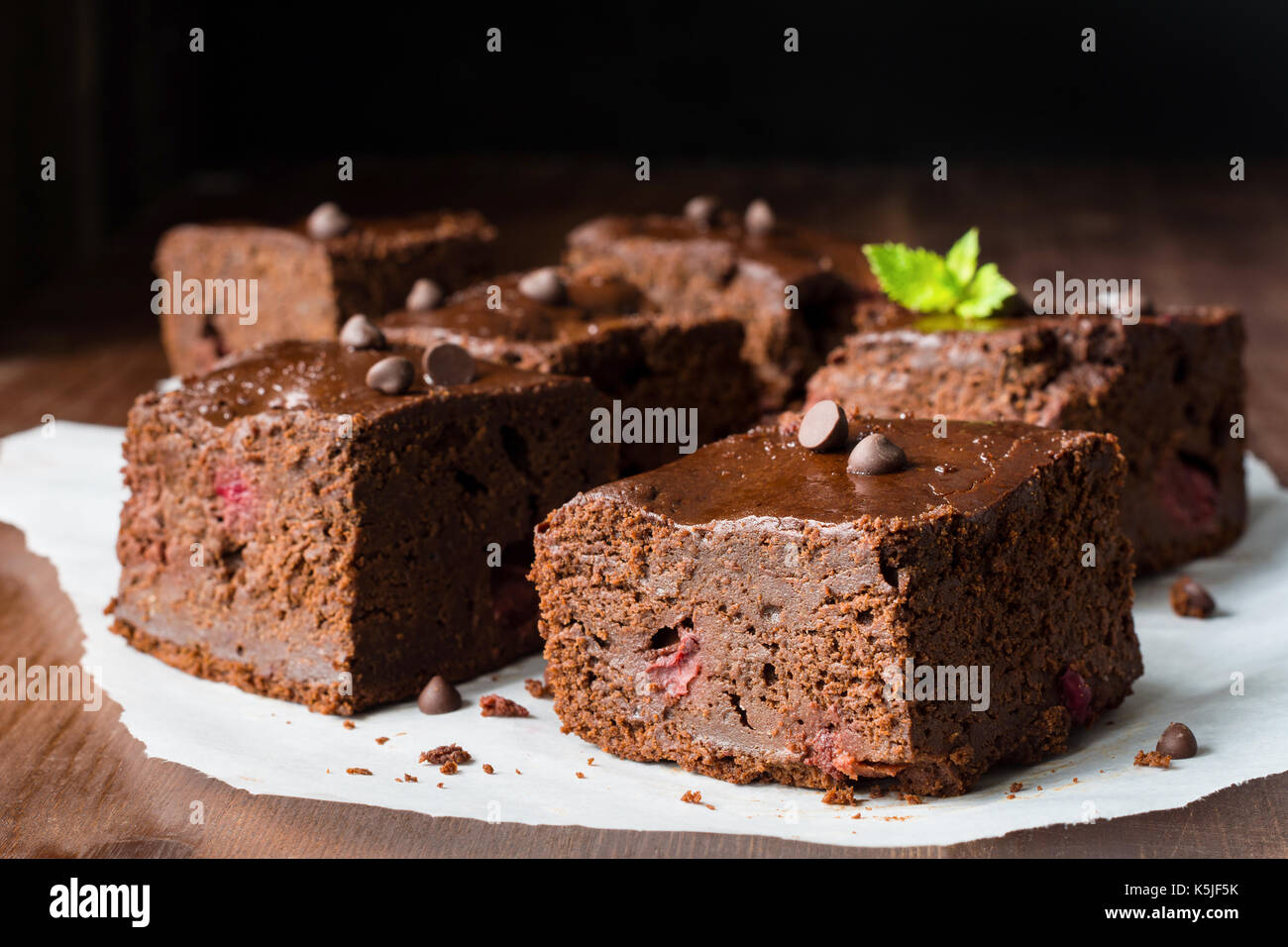 Dark chocolate brownies decorated with mint leaf on wooden table. Closeup view horizontal