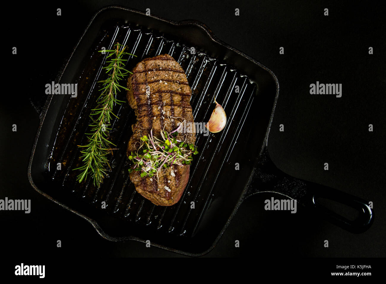 Grilled beef steak in a pan on the black background Stock Photo