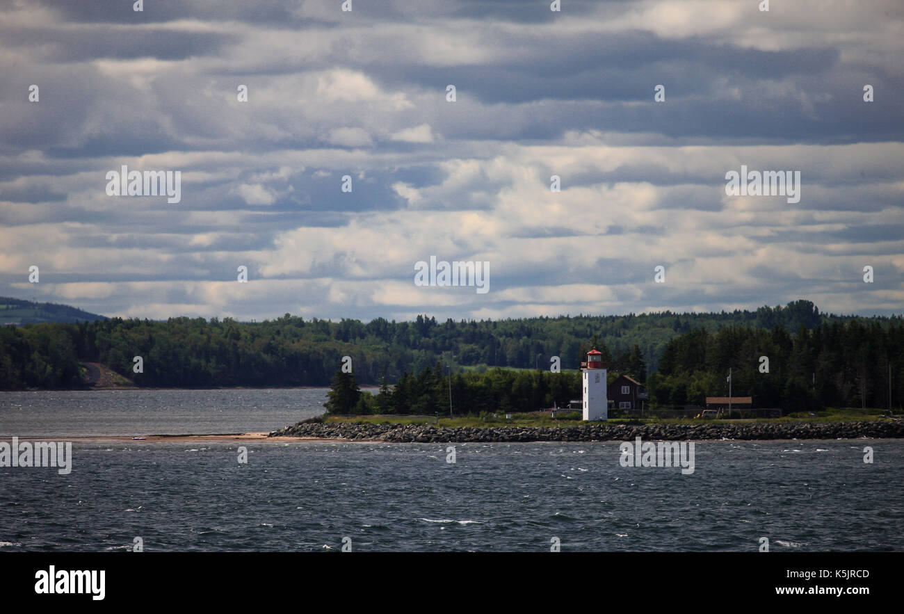 A lighthouse sits on the north western shoreline of Nova Scotia, Canada as seen from a passenger ferry crossing the Northumberland Straight. Stock Photo