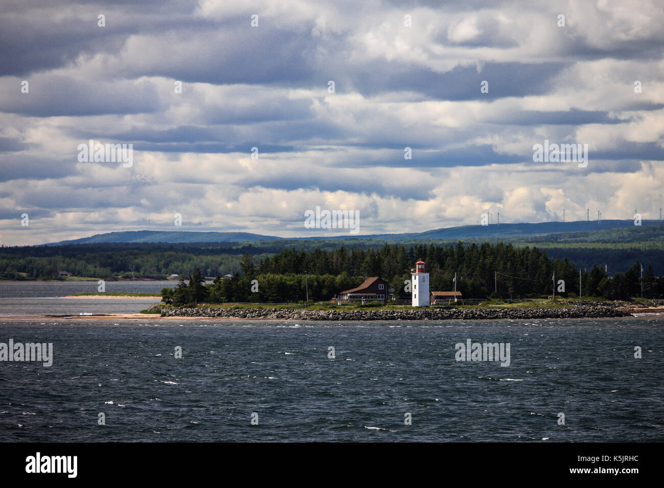 A lighthouse sits on the north western shoreline of Nova Scotia, Canada as seen from a passenger ferry crossing the Northumberland Straight. Stock Photo