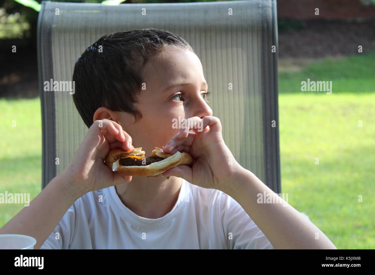 Boy eating a burger Stock Photo Alamy