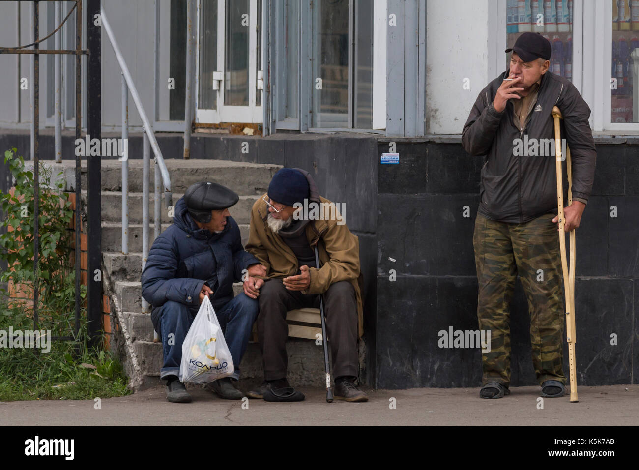 KAZAN, RUSSIA - 9 SEPTEMBER 2017: three homeless beggars men having a break near food shop Stock Photo