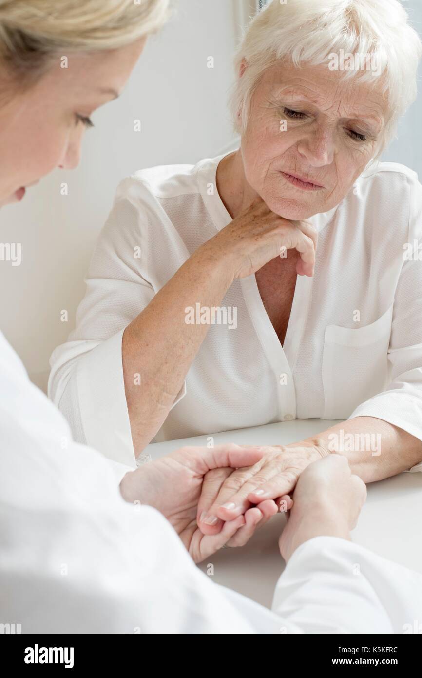 Female doctor examining senior patient's hand. Stock Photo