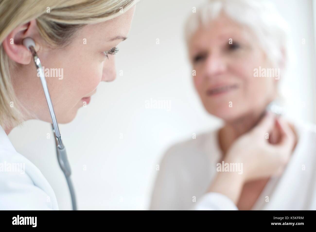 Female doctor wearing stethoscope, listening to patient Stock Photo Alamy