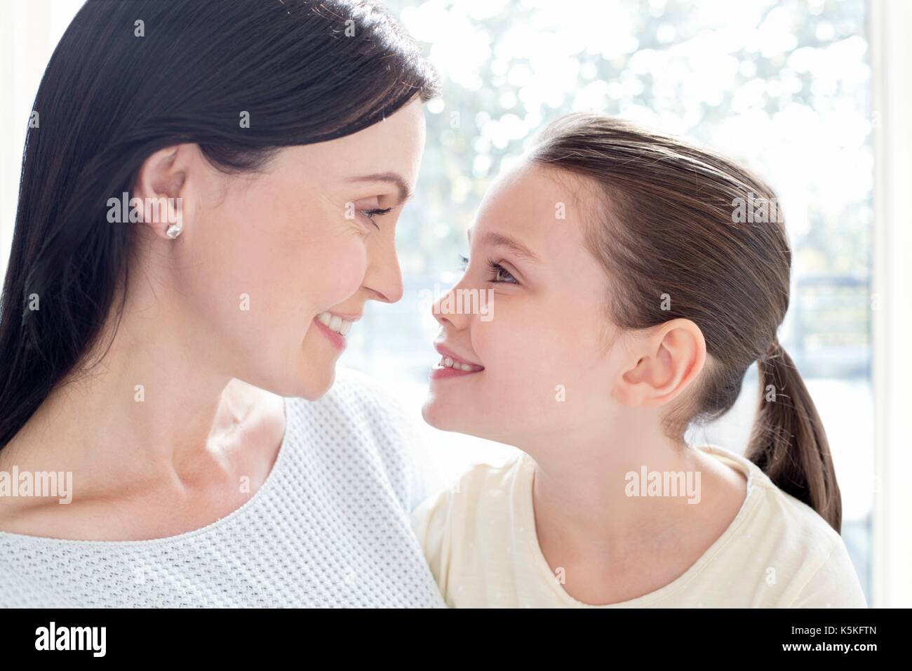 Mother and daughter face to face, smiling. Stock Photo