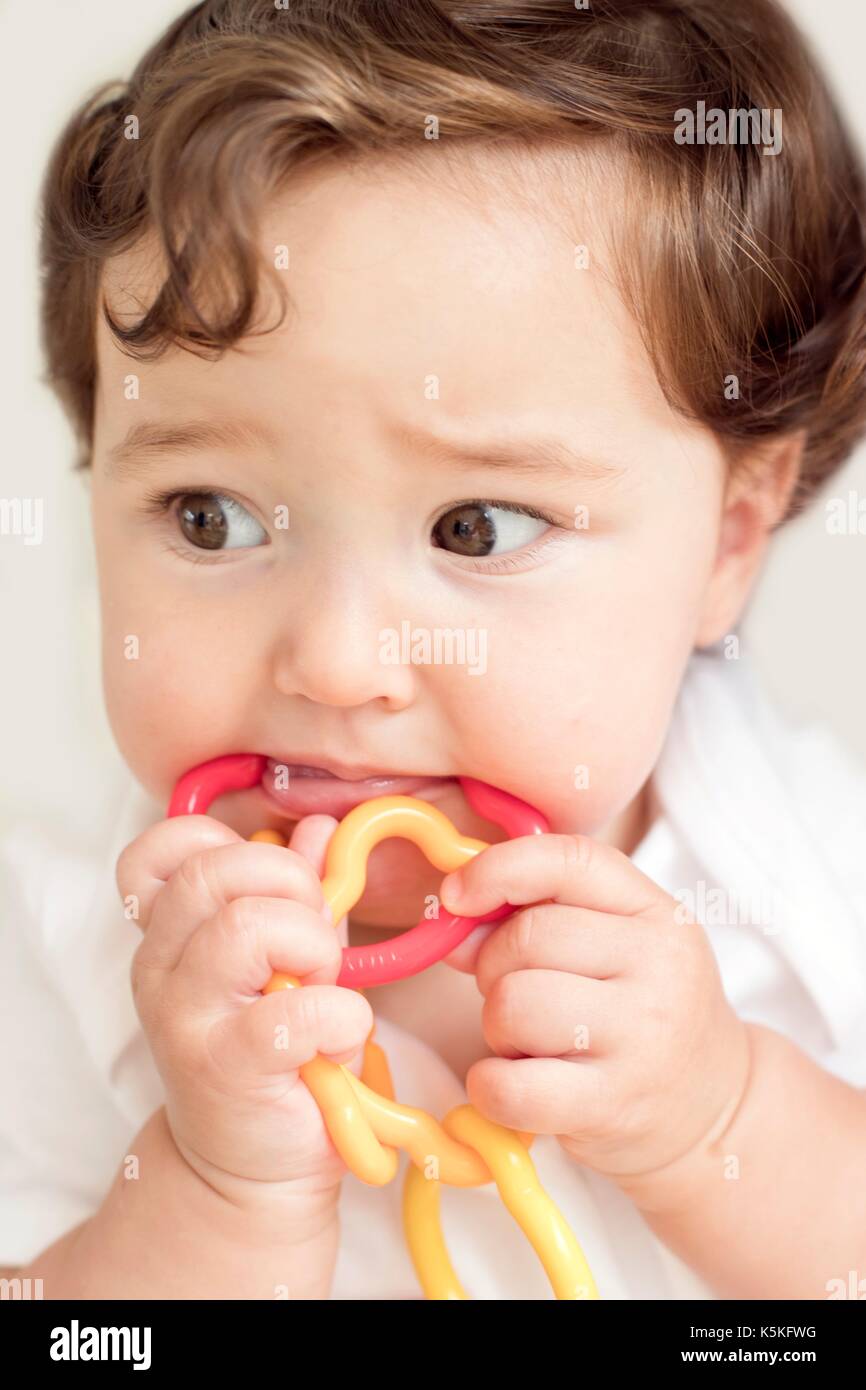 Female toddler chewing rattle. Stock Photo