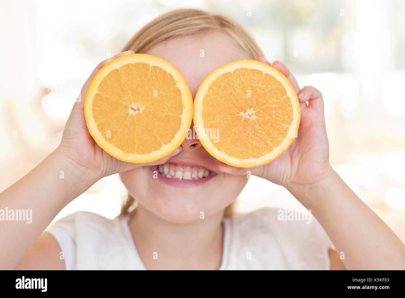 Young girl holding oranges over eyes. Stock Photo