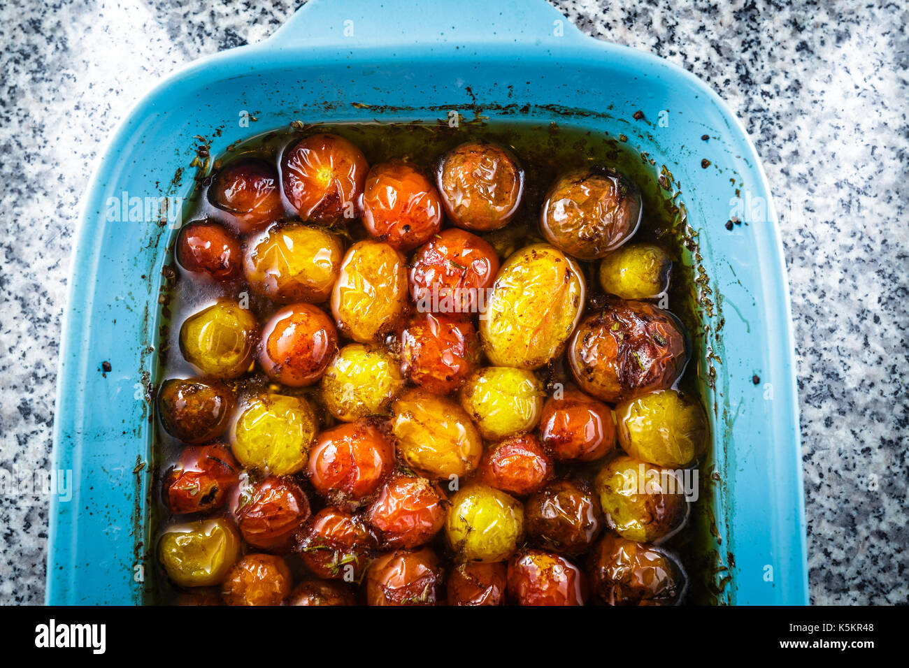 Roasted cherry tomatoes in a blue baking dish.  The cherry tomatoes are roasted with extra virgin olive oil, balsamic vinegar, and a touch of brown Su Stock Photo