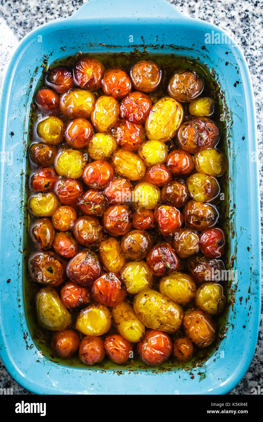 Roasted cherry tomatoes in a blue baking dish. The cherry tomatoes are roasted with extra virgin olive oil, balsamic vinegar, and a touch of brown Su Stock Photo