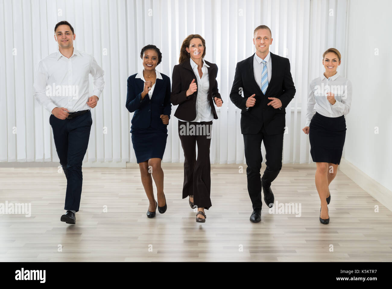 Group Of Professional Businesspeople Together Running In Office Stock Photo