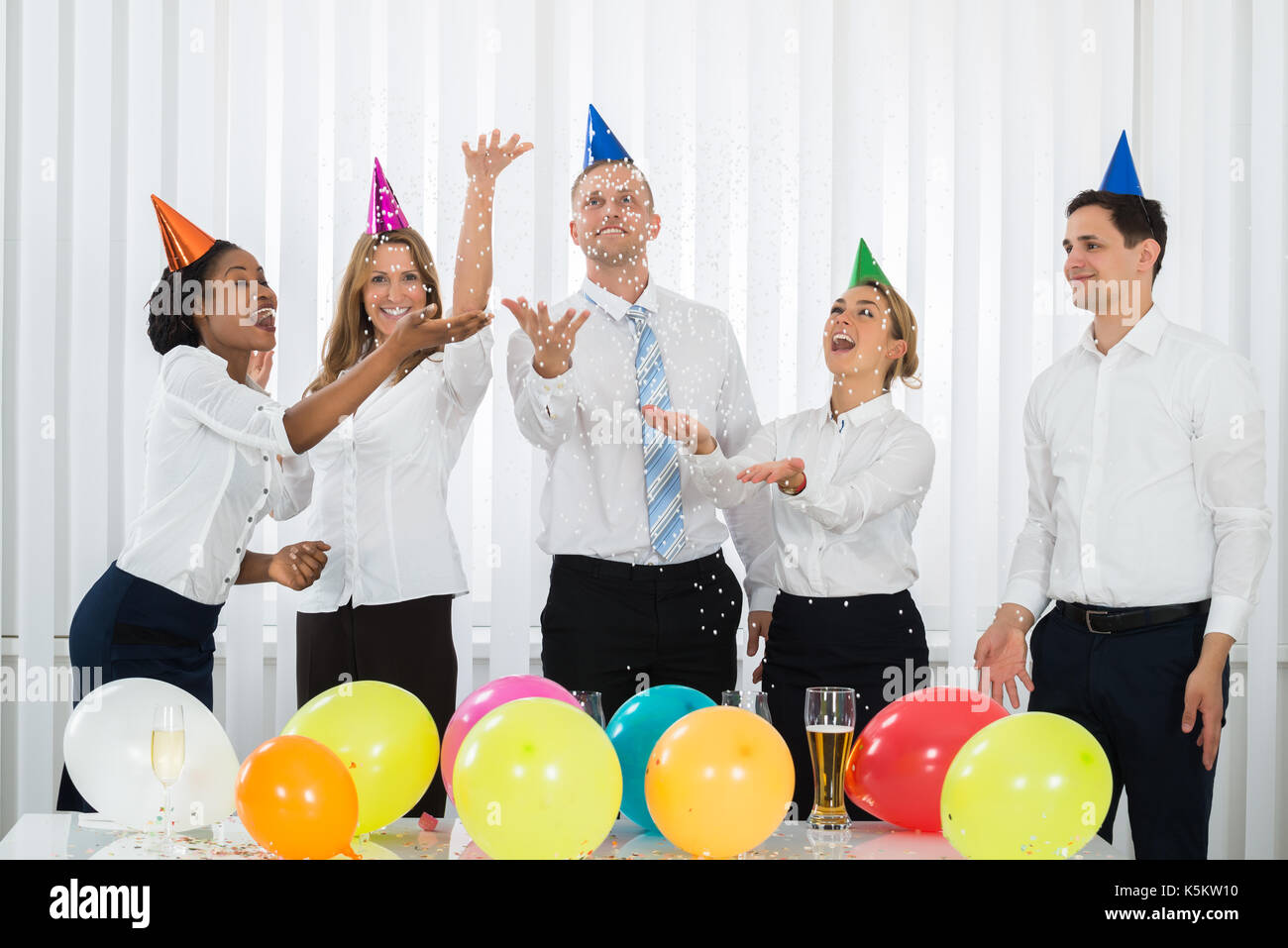 Group Of Businesspeople Standing Under Falling Confetti In Party Stock Photo