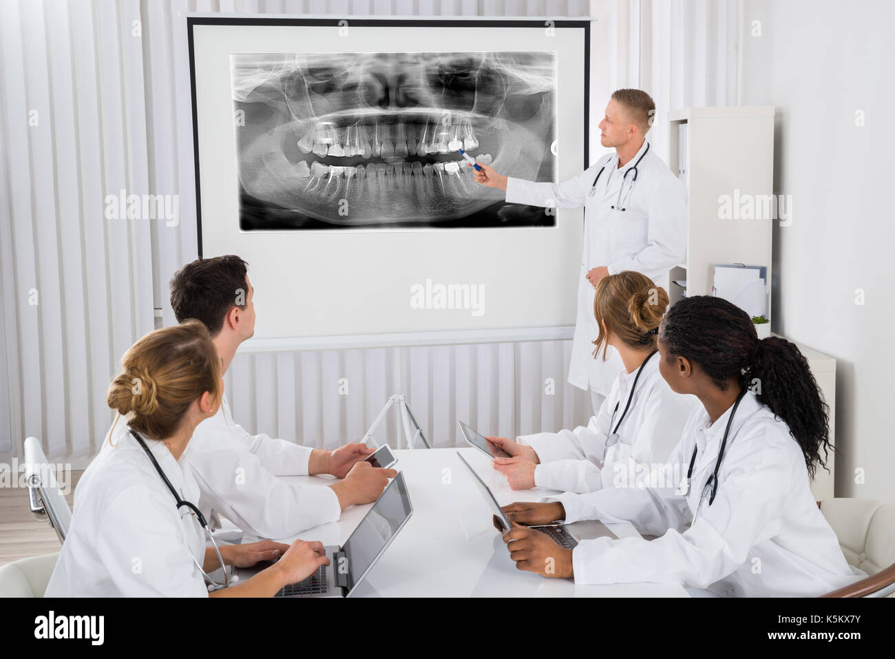 Young Male Doctor Explaining Human Teeth X-ray To His Colleagues Stock Photo