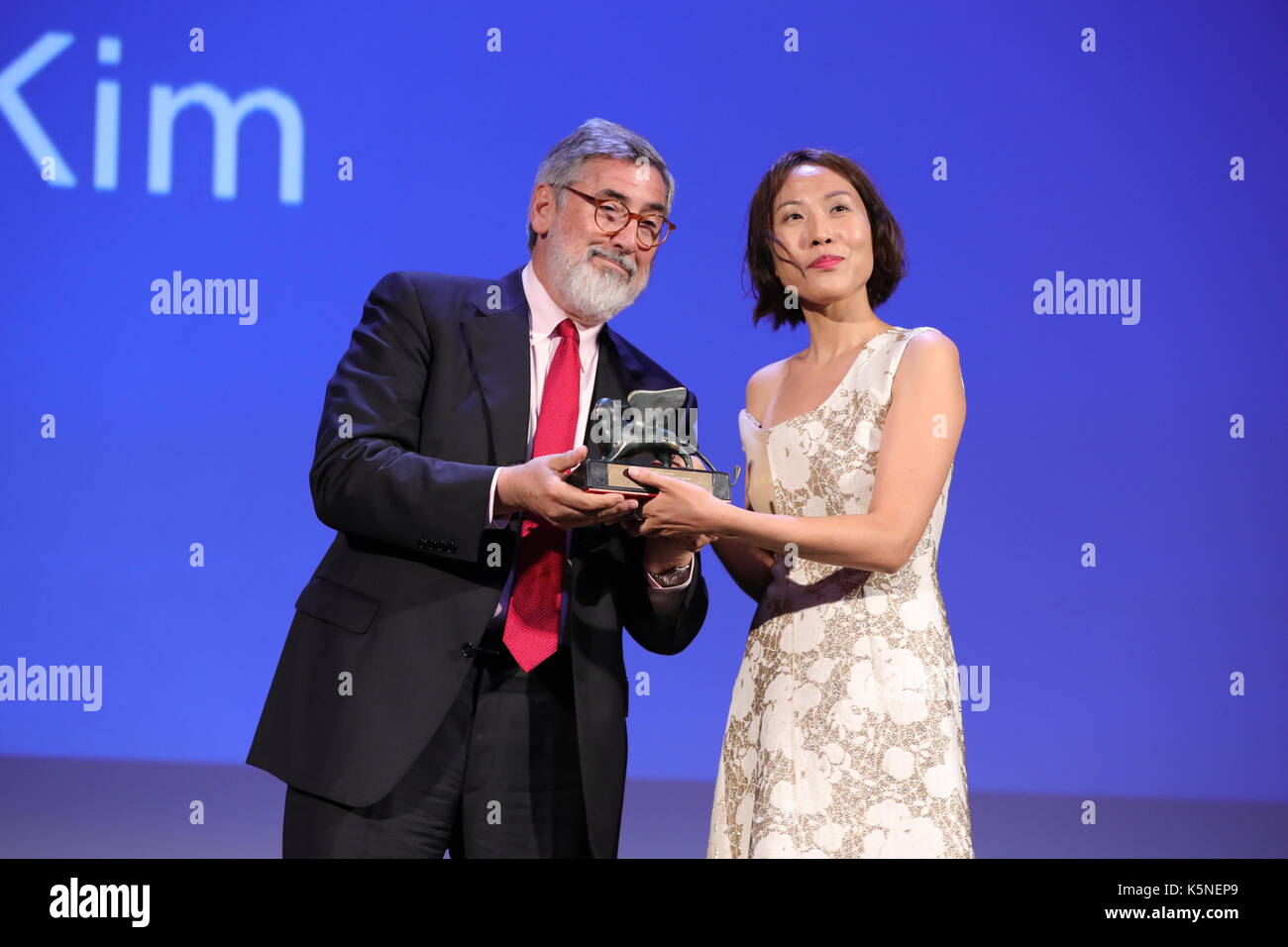 VENICE, ITALY - SEPTEMBER 09: Gina Kim receives from John Landis the Best VR (Virtual Reality) award for the movie 'Bloodless' during the award ceremony of the 74th Venice Film Festival on September 9, 2017 at Venice Lido. Stock Photo