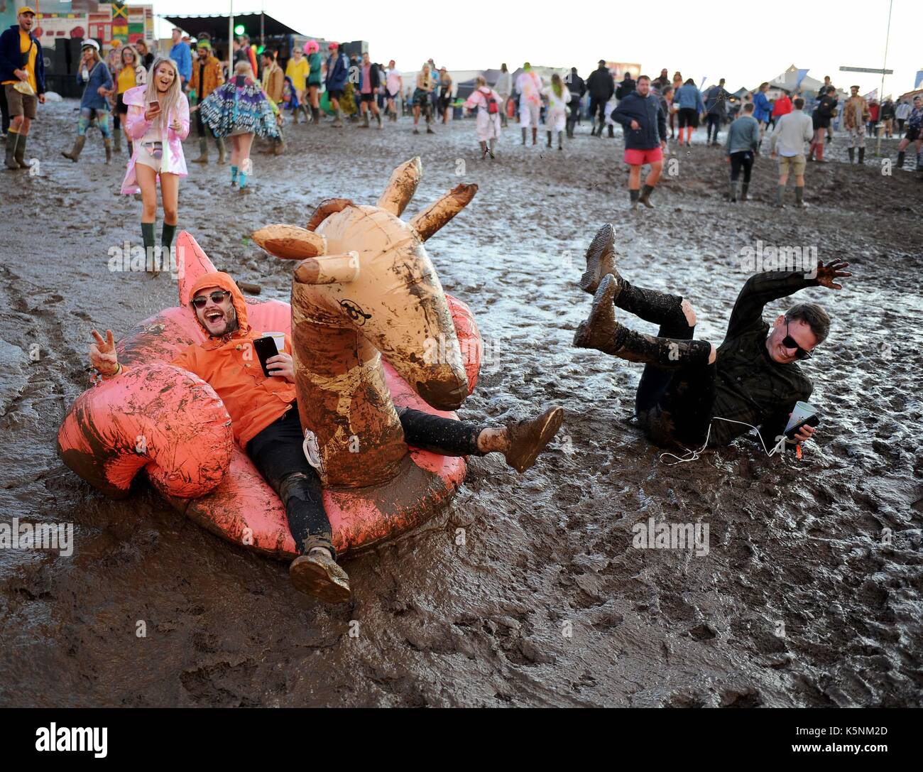 Lulworth Estate, Dorset, UK. 9th September, 2017. Bestival Music Festival. Festival goers enjoy the muddy conditions riding an inflatable down the slope Credit: Finnbarr Webster/Alamy Live News Stock Photo