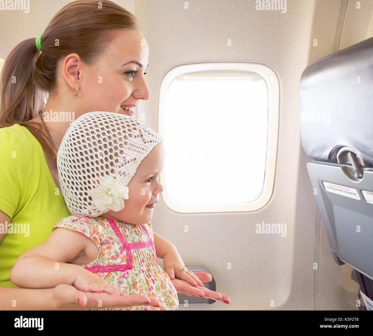 Airplane flight from inside. Woman and kid travelling together. Stock Photo