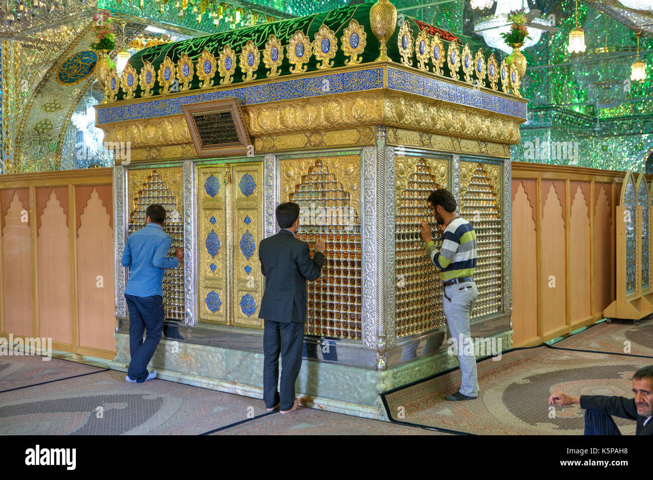 Fars Province, Shiraz, Iran - 18 april, 2017:  Mirrored mausoleum in  Sayyed Alaeddin Hossein Mosque, Iranian men worship an Islamic shrine. Stock Photo