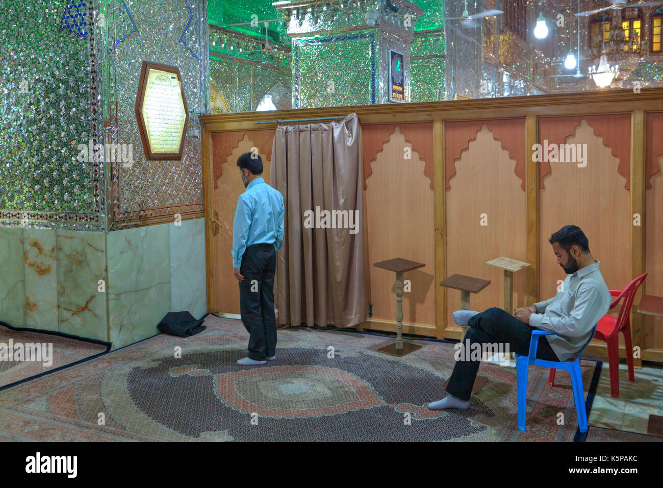 Fars Province, Shiraz, Iran - 18 april, 2017:  Prayer hour in mosque, Mirrored mausoleum of Sayyed Alaeddin Hossein, two Muslim men perform Islamic re Stock Photo