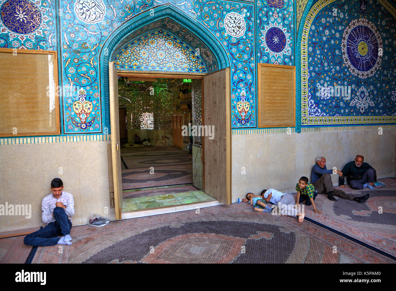 Fars Province, Shiraz, Iran - 18 april, 2017:  Mirrored mausoleum and Mosque of Sayyed Alaeddin Hossein, Muslim parishioners sit in front of the entra Stock Photo